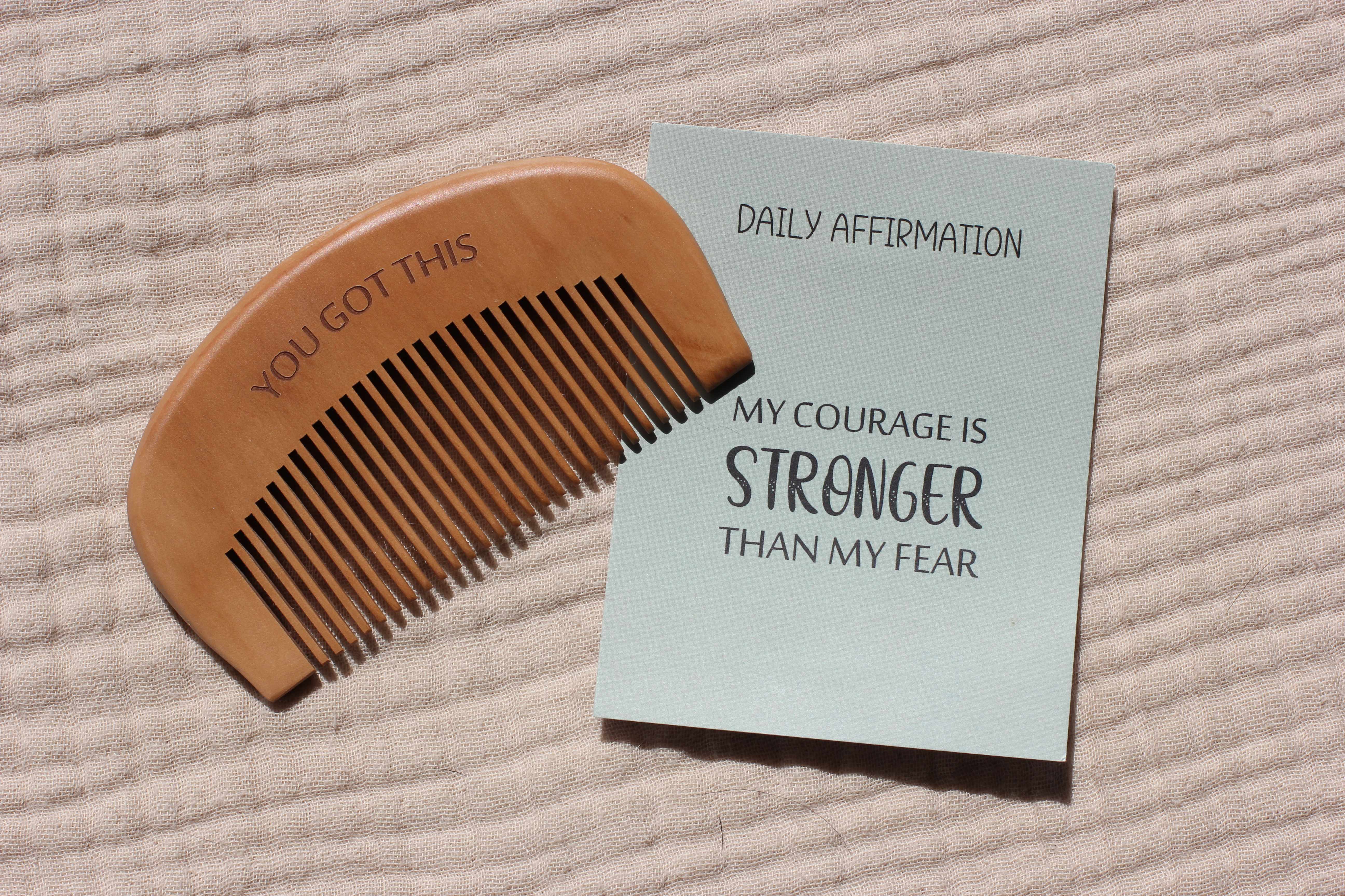 The wooden birth comb engraved with 'You Got This' resting beside the Daily Affirmation card that reads 'My Courage Is Stronger Than My Fear'