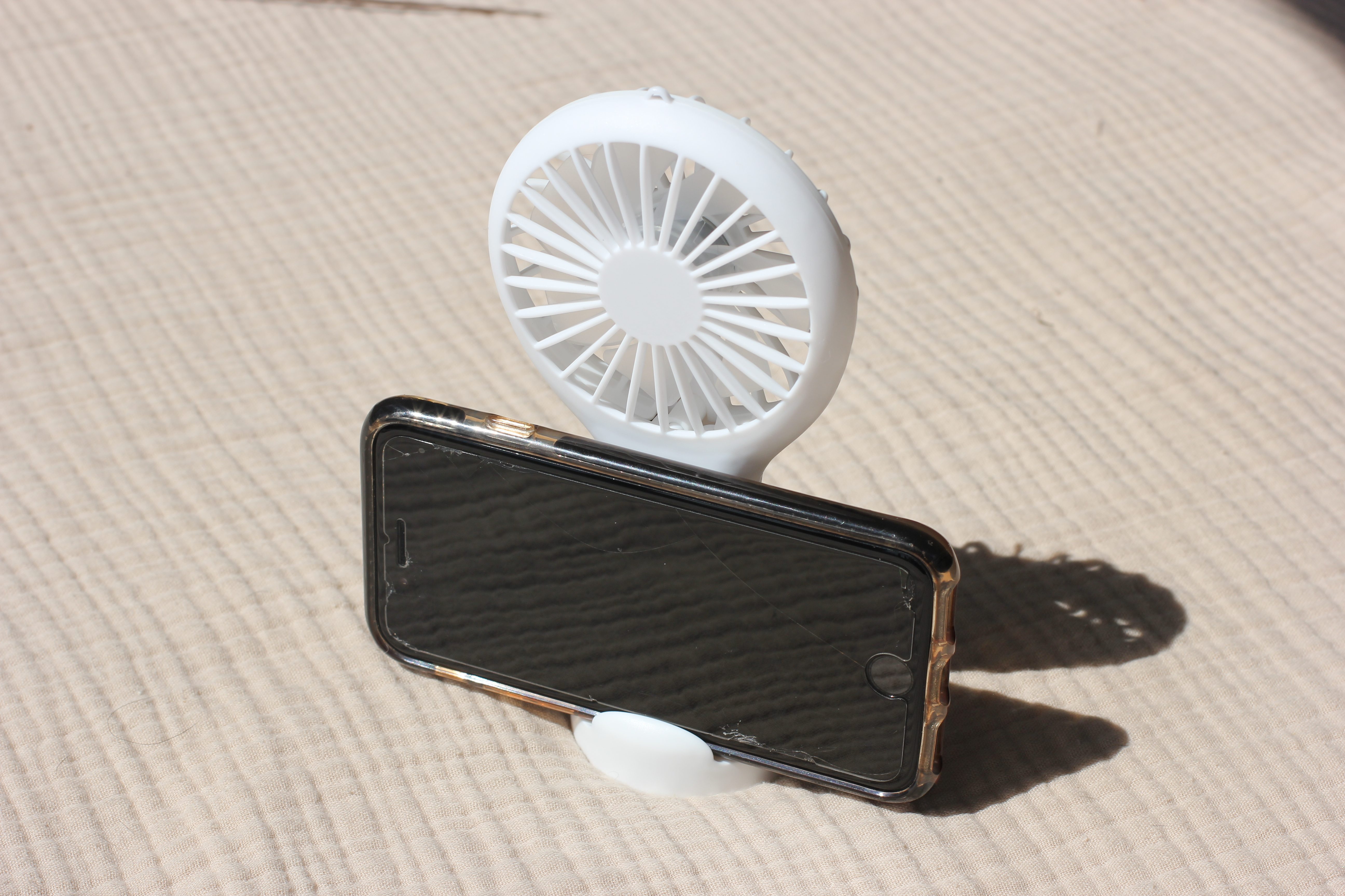The rechargeable mini fan with its built-in phone stand propping up a phone