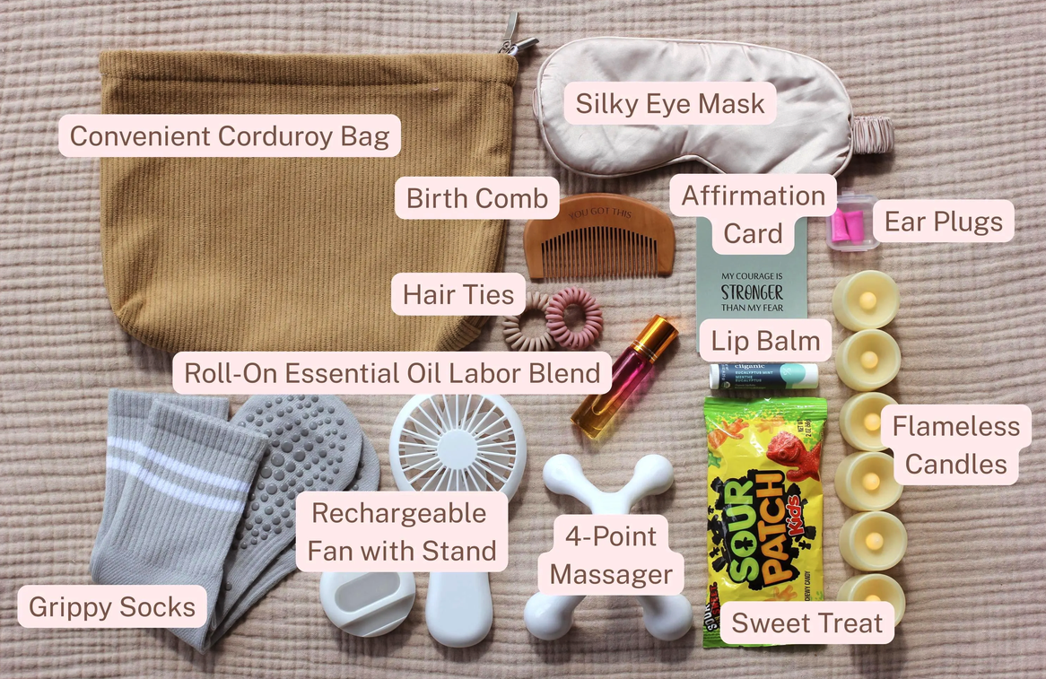 Complete Labor Comfort Kit laid out and labeled, including a corduroy bag, silky eye mask, wooden birth comb, affirmation card, ear plugs, hair ties, lip balm, roll-on essential oil labor blend, flameless candles, grippy socks, rechargeable fan with stand, 4-point massager, and a sweet treat