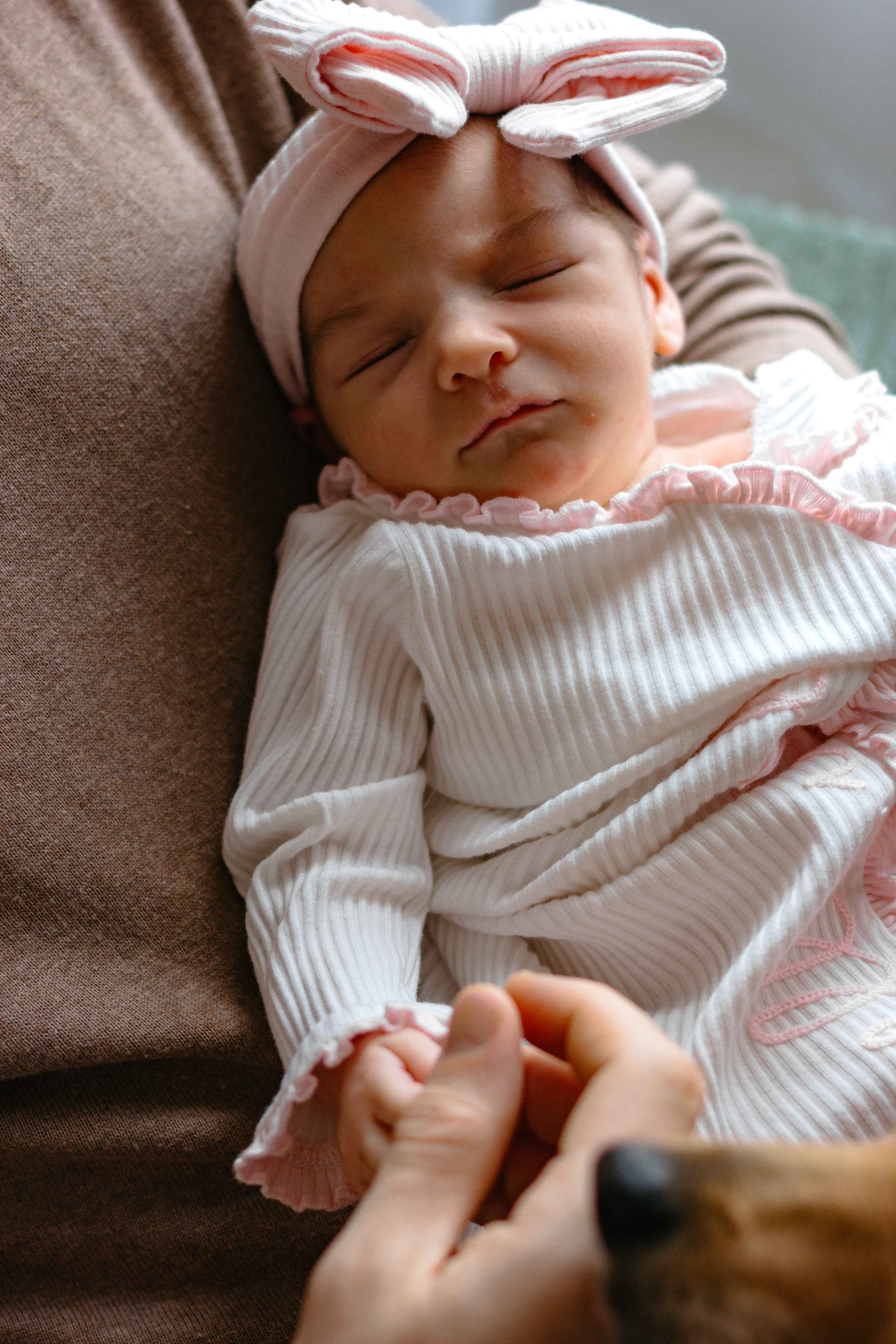 Smiling newborn in pink striped outfit with bow