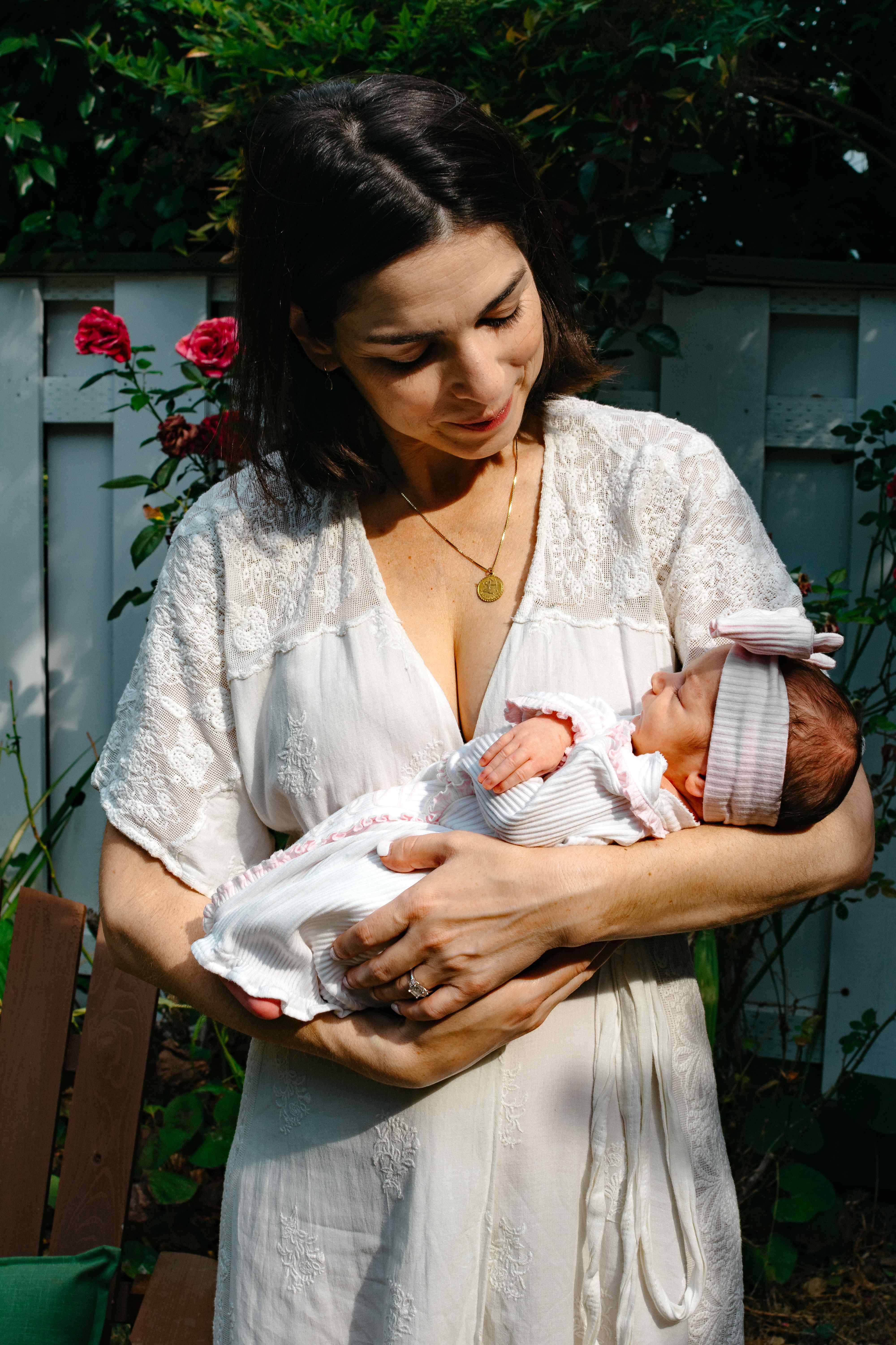 Mother in white dress with newborn in garden