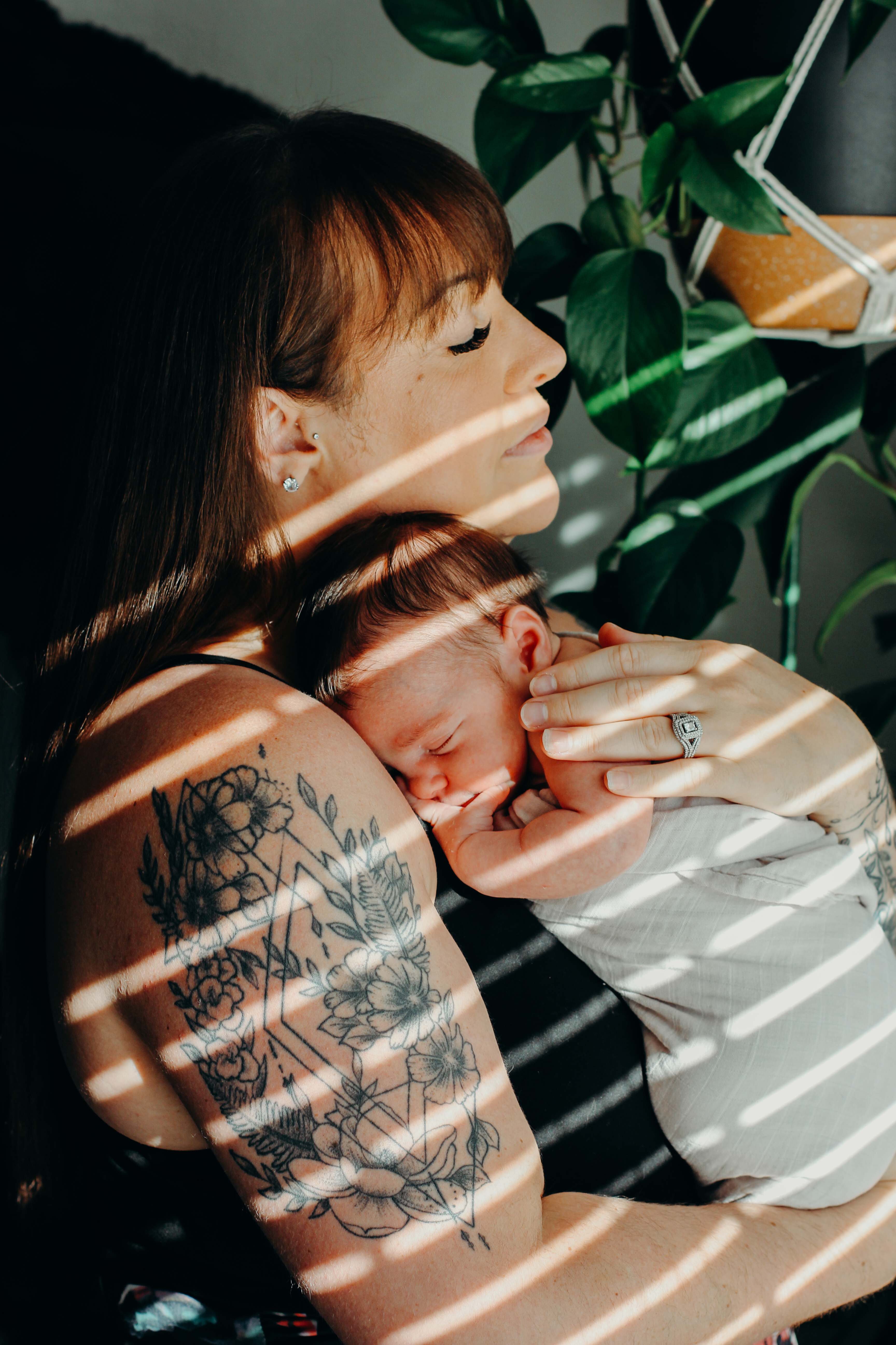 Mother with back tattoo holding newborn