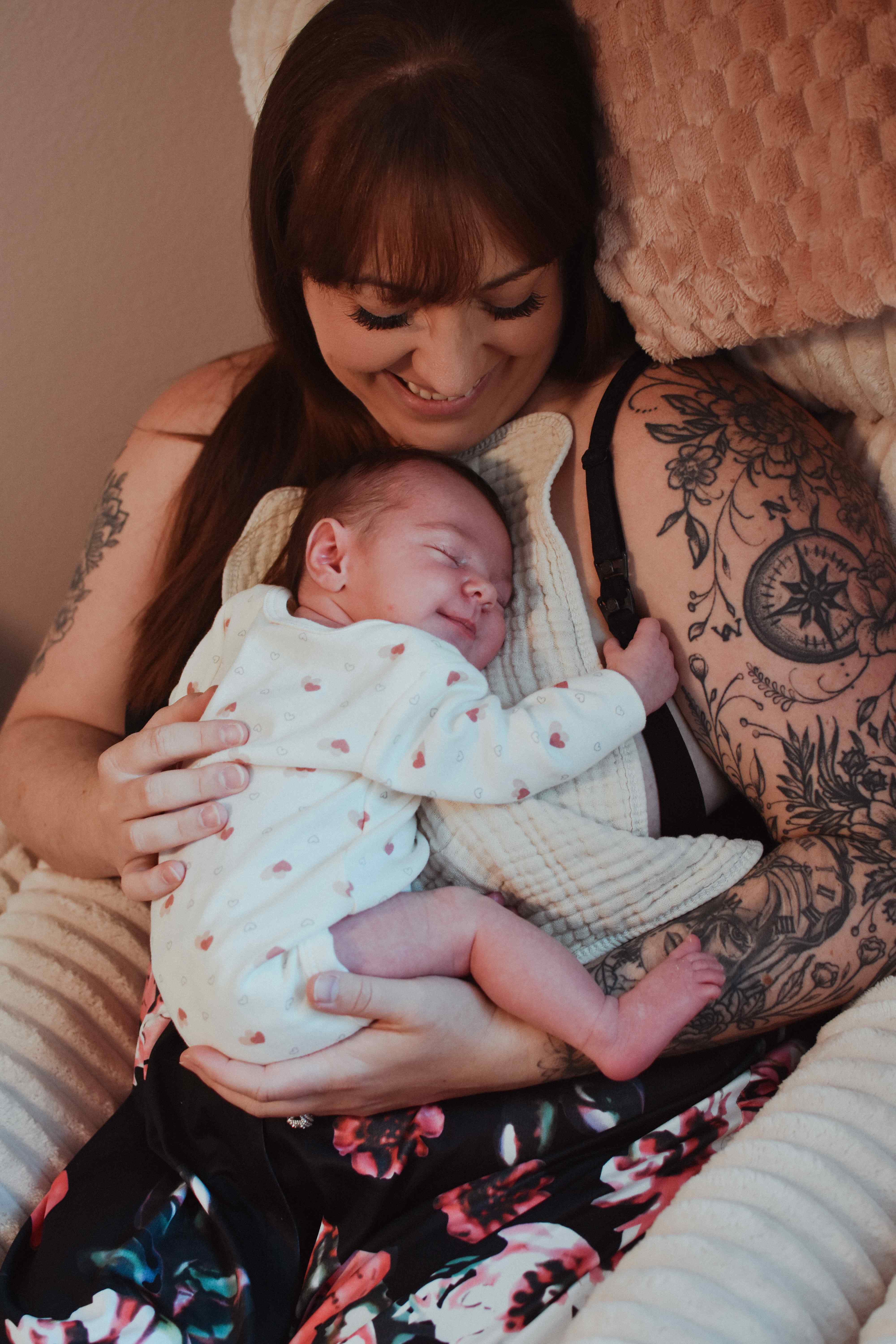 Mother with tattoos holding newborn